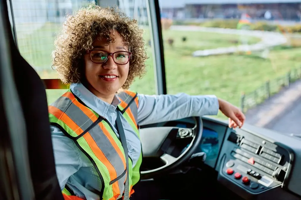 Happy female bus driver at work looking at camera.